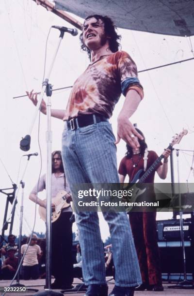 Full-length portrait of English singer Joe Cocker, wearing a tie-dyed shirt and blue jeans, performing at the Woodstock Music Festival in Bethel, New...