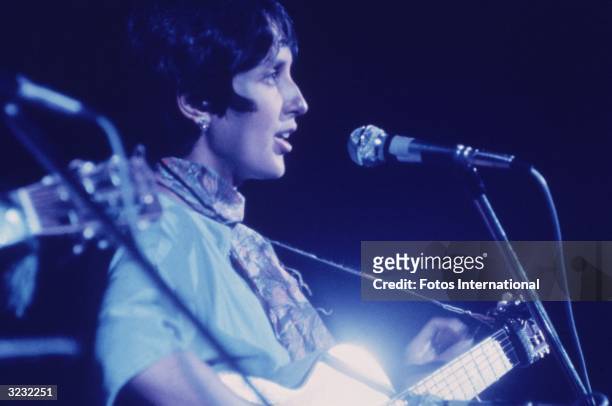 Profile of American folk musician Joan Baez singing and playing the guitar at the Woodstock Music Festival, Bethel, New York.