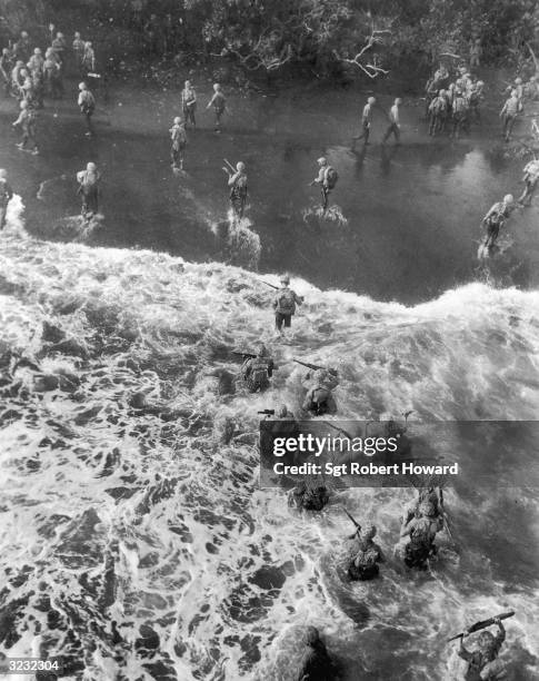 Marines wallow through the surf for a landing on the beach at Cape Gloucester, New Britain Island, Papua, New Guinea, World War II. They hold their...