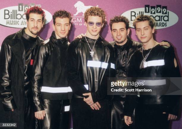 American pop group 'N Sync, wearing matching black leather outfits, posing in front of a wall of logos at the 1999 Billboard Music Awards, MGM Grand...