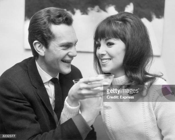 American actor Marlo Thomas and British actor Daniel Massey , each holding martini glasses, smile with arms intertwined in a toast. Thomas and Massey...