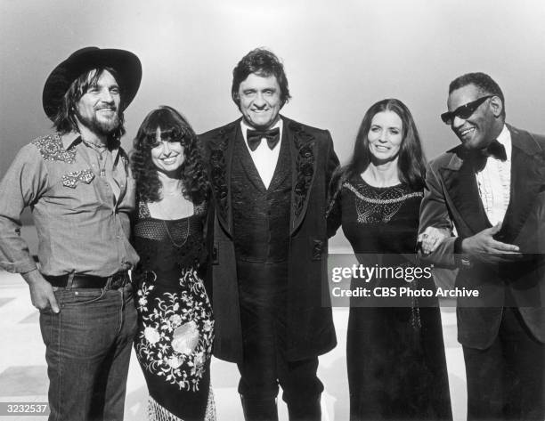 American country singer Johnny Cash stands with his guests Waylon Jennings ; Jessi Colter; his wife, June Carter Cash ; and singer Ray Charles, in a...