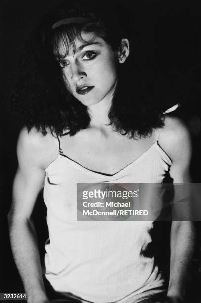 Studio portrait of future American pop singer Madonna tilting her head to one side while wearing a cotton camisole and a headband, New York City. Her...