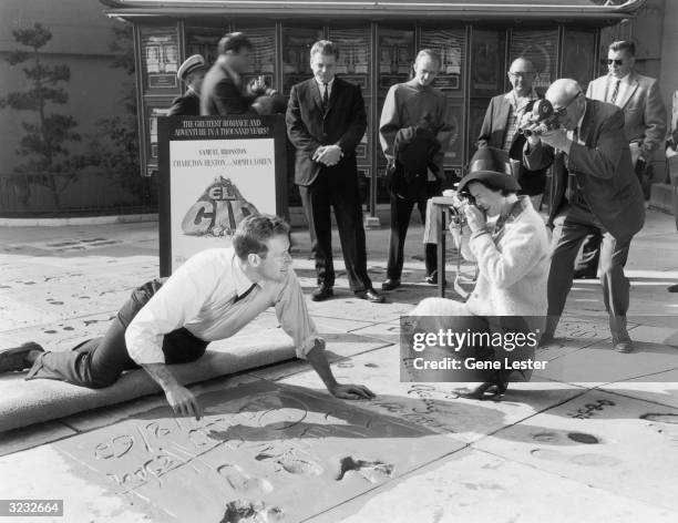 American actor Charlton Heston smiles for photographers as he signs his name on his square along the Hollywood Walk of Fame, Grauman's Chinese...