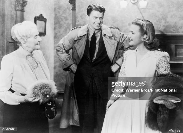 American actor and politician Ronald Reagan smiles at actor Priscilla Lane as actor May Robson looks on in a still from director Curtis Bernhardt's...
