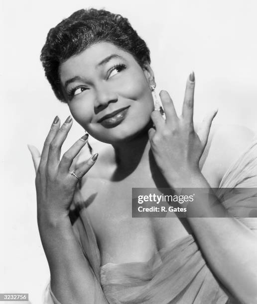 Studio portrait of American singer Pearl Bailey posing in a low-cut evening dress, 1940s.