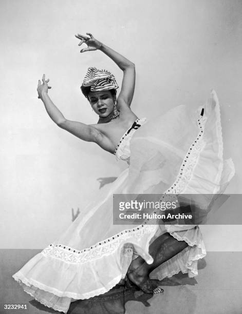 Full-length portrait of American dancer and choreographer Katherine Dunham bending her knees and holding her hands above her head in an...