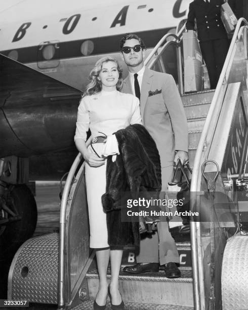 British actor Anthony Steel and his wife, Swedish-born actor Anita Ekberg smile as they disembark from an airplane, arriving from London at New York...