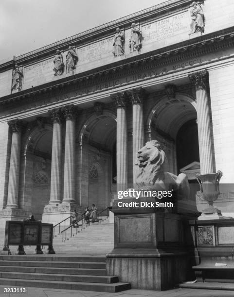Front exterior view of the New York Public Library, Fifth Avenue, looking up the front steps, with one of the lion statues perched on the front...