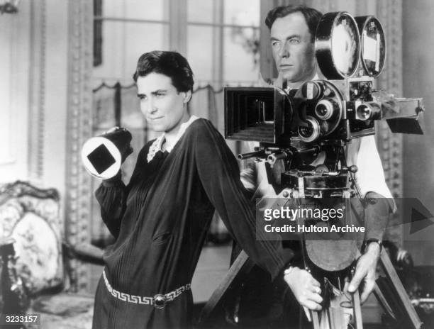 American film director Dorothy Arzner and Alfred Gilks, her cinematographer, survey a scene as they stand by a camera on the set of her film, 'Get...