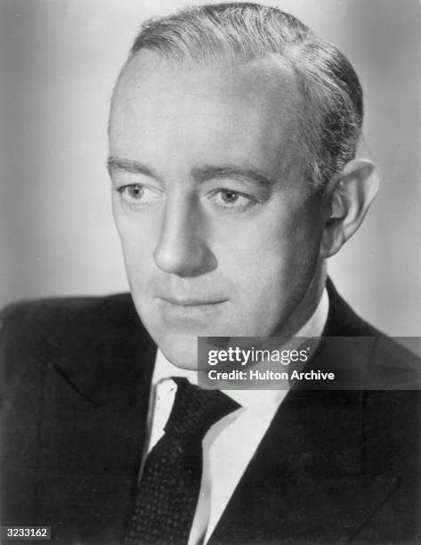 Headshot of British actor Alec Guinness wearing a suit and tie, in a promotional portrait for director Ronald Neame's film, 'The Horse's Mouth'.