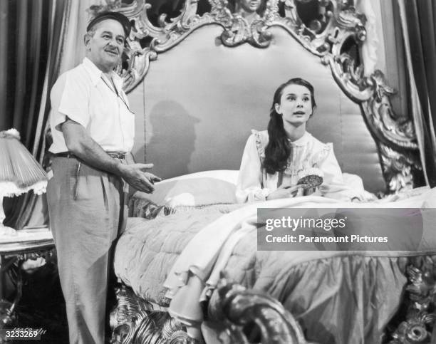 French-born director William Wyler directs Belgian-born actor Audrey Hepburn on the set of his film, 'Roman Holiday'. Hepburn is sitting up in bed...