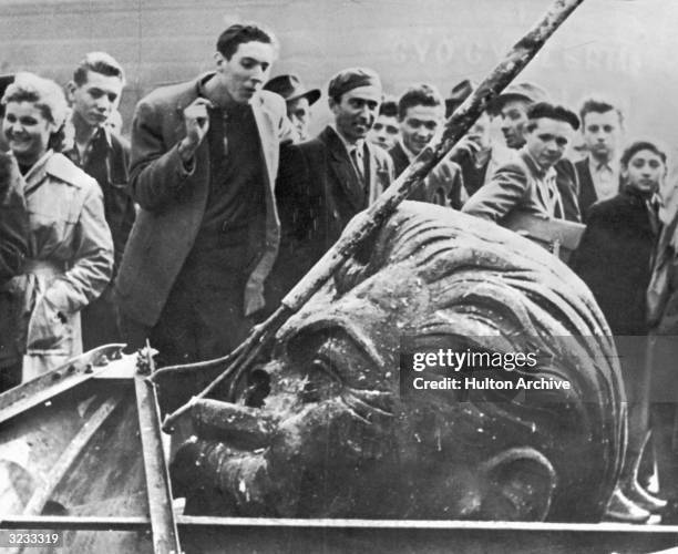 Crowd of people surround the demolished head of a statue of Josef Stalin, including Daniel Sego, the man who cut off the head, during the Hungarian...