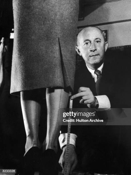 French fashion designer Christian Dior demonstrates with a tape measure and a model how he revolutionized fashion by lowering hemlines, Paris, France.