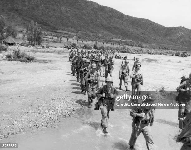 Troops of the 1st Cavalry Division cross a stream as they move into front lines in Korea during the Korean War.