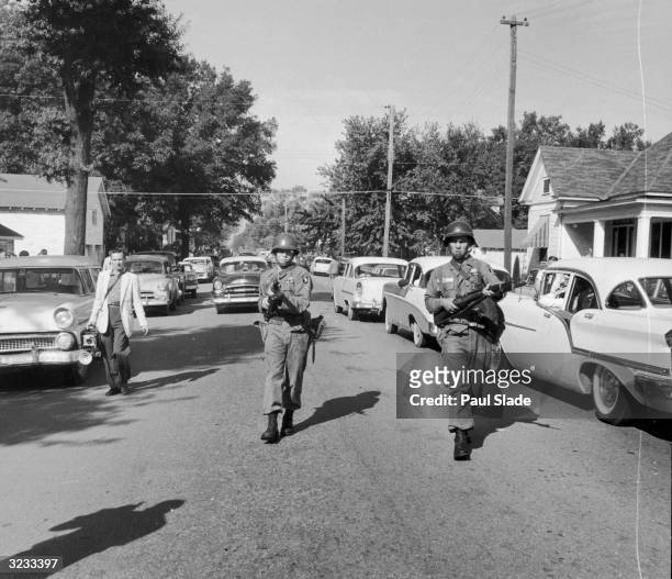 Two National Guardsmen proceed down a street with their guns drawn in order to enforce the nation's first desegregation at Central High School in...