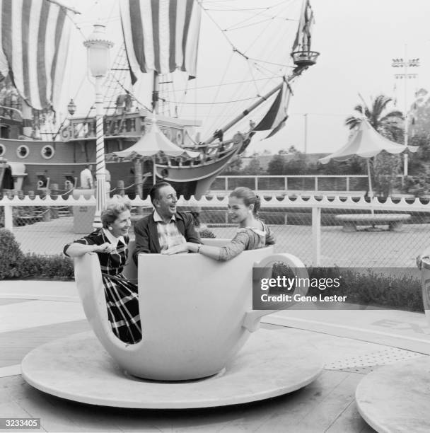 American animator and producer Walt Disney and his wife, Lillian, and their daughter, Diane, ride a spinning tea cup at Disneyland, shortly after its...