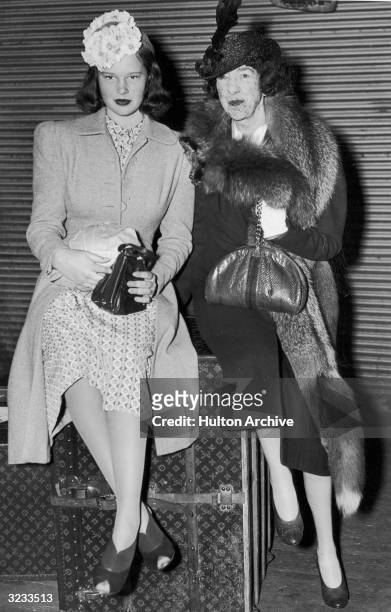 American heiress Gloria Vanderbilt and her aunt, Gertrude Vanderbilt Whitney , sit on top of a Louis Vuitton trunk after returning from a cruise.