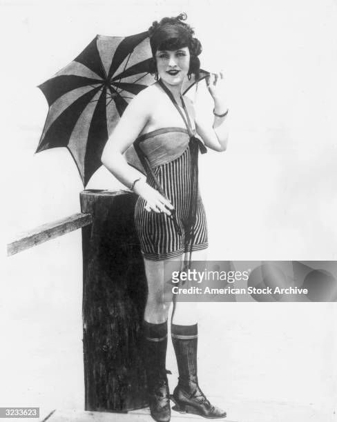 Bathing beauty' from film director/producer Mack Sennett's stable wearing halter-style striped swimsuit, knee socks and laceup shoes, poses with a...