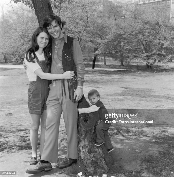 Portrait of casting director Mary Jo Slater and actor Michael Hawkins hugging, while their son, future actor Christian Slater , climbs a tree in...