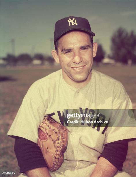 Portrait of American baseball player Yogi Berra in his New York Yankees uniform with a baseball glove under his arm, New York City.