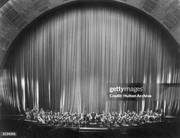Hungarian-born composer and conductor Erno Rapee poses with the Music Hall Symphony Orchestra at Radio City Music Hall, Rockefeller Center, New York...
