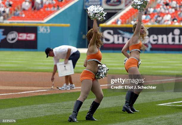 The Florida Marlins Mermaids show off their new outfits while a grounds crew memebr installs the first base bag prior to the start of their game...