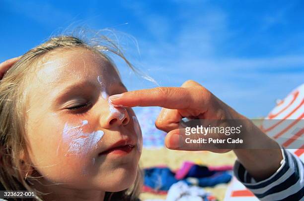 girl (4-6),eyes closed,having sun block applied to cheeks and nose - sun on face stock-fotos und bilder