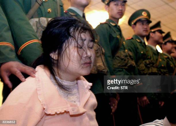Zhao Ailong , who was convicted as part of a gang responsible for the killing of ten people, holds back tears as she kneels before a sentencing...