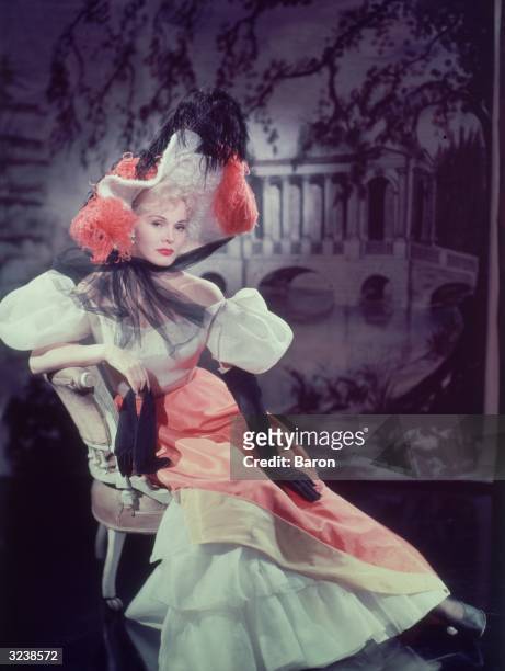 Hungarian actress Zsa Zsa Gabor wearing an elaborate costume with a feathered hat and black gloves, possibly from the 1952 film 'Moulin Rouge'.