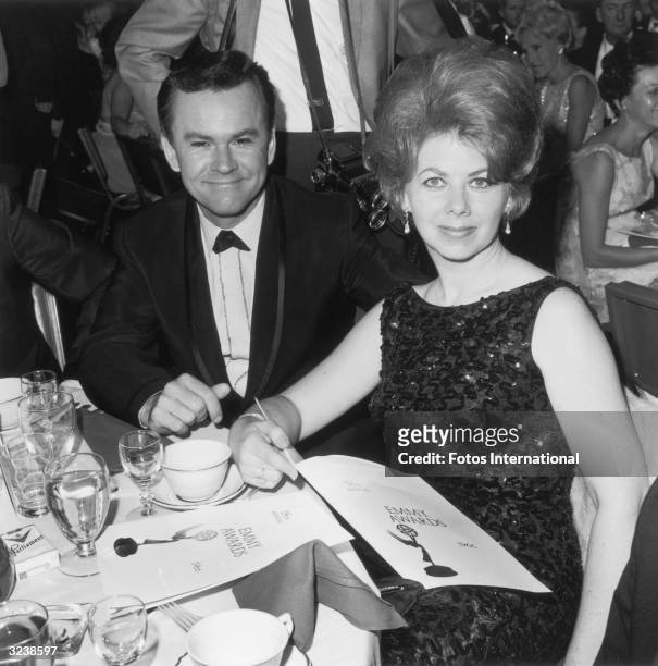American actor Bob Crane sitting with his wife, Anne Terzian, at the Emmy Awards, Hollywood, California. Terzian is holding an open Emmy Award...