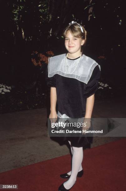 Full-length view of American actor Drew Barrymore standing on a red carpet at a Radie Harris Luncheon Tribute, Beverly Hills Hotel, California. She...