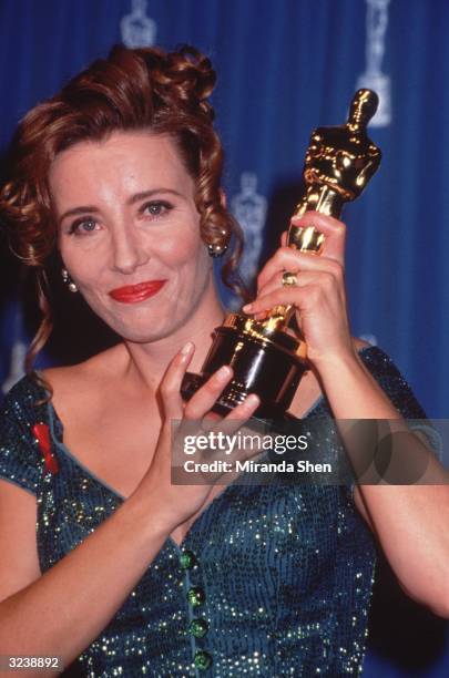 British actor Emma Thompson smiles as she holds up her Oscar statuette at the Academy Awards, Dorothy Chandler Pavilion, Los Angeles, California....