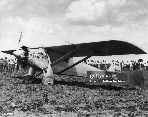 Crowd stands in a field behind The Spirit of St Louis, the airplane in which American aviator Charles Lindbergh completed the first nonstop...