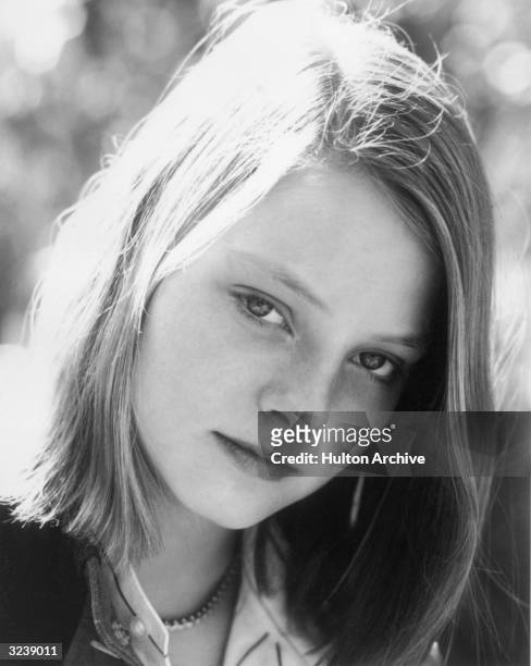 Outdoor headshot portrait of American actor Jodie Foster as a teenager, with the sun highlighting her hair.