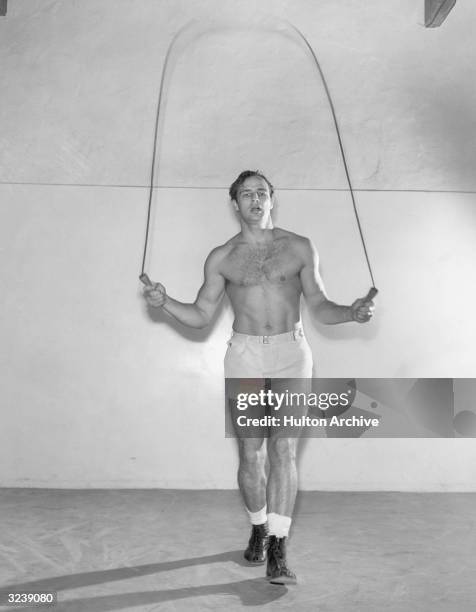 American actor Marlon Brando jumps rope wearing boots, shorts and no shirt.