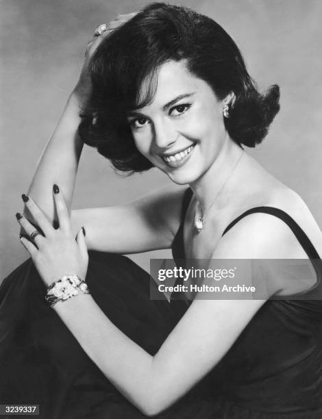 American actor Natalie Wood, wearing a black evening dress, smiles while posing in a promotional portrait for director Michael Anderson's film, 'All...