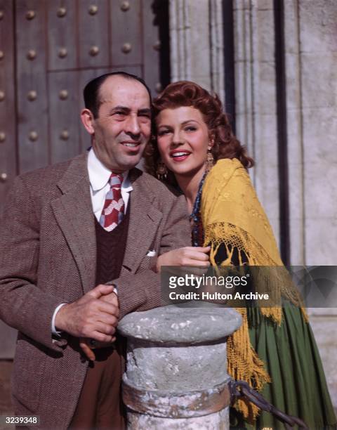 Portrait of American actor Rita Hayworth and her father, Spanish-born dancer Eduardo Cansino , linking their arms together while leaning on a stone...
