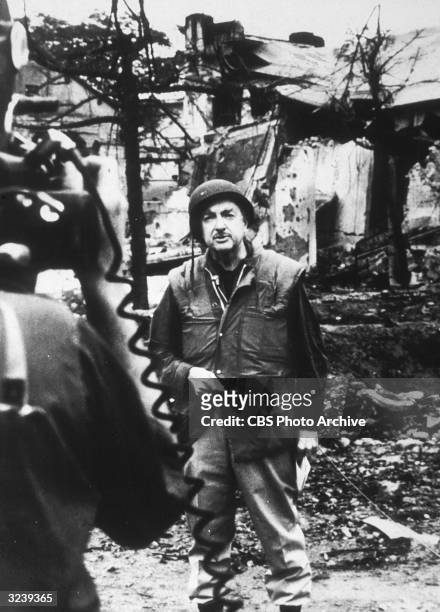 American broadcast journalist Walter Cronkite gives a report in a bombed out area while covering the Vietnam War for CBS News,