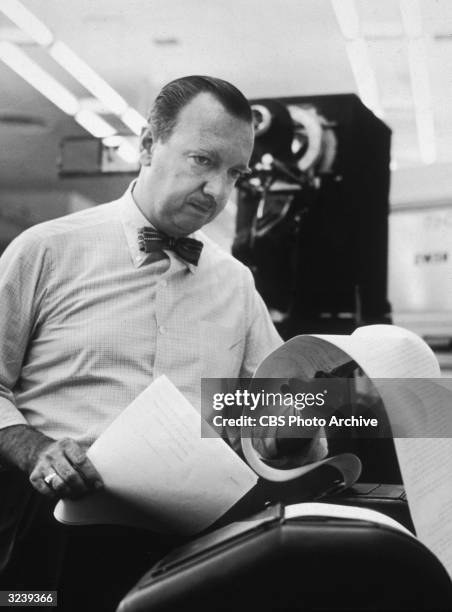 American broadcast journalist Walter Cronkite looks at the wire service reports in the CBS newsroom.