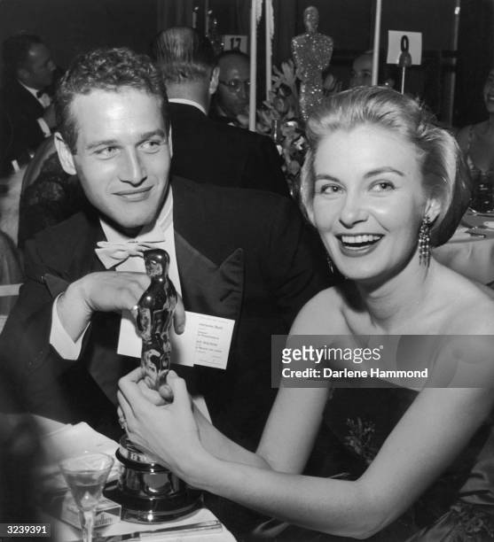 American actor Joanne Woodward holds her Oscar statuette while sitting next to husband, American actor Paul Newman, during the Governor's Ball, an...