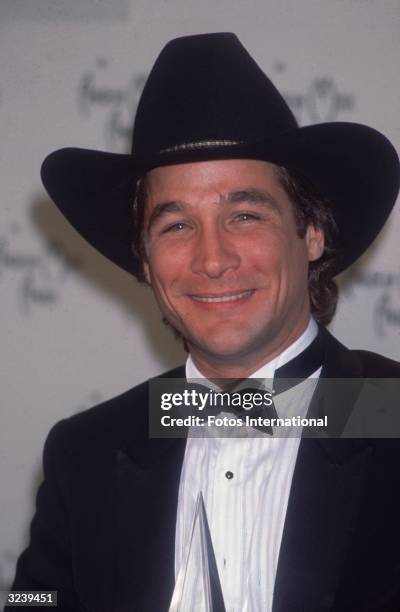 Headshot of American country singer and songwriter Clint Black wearing a tuxedo and a black cowboy hat at the American Music Awards, Los Angeles,...