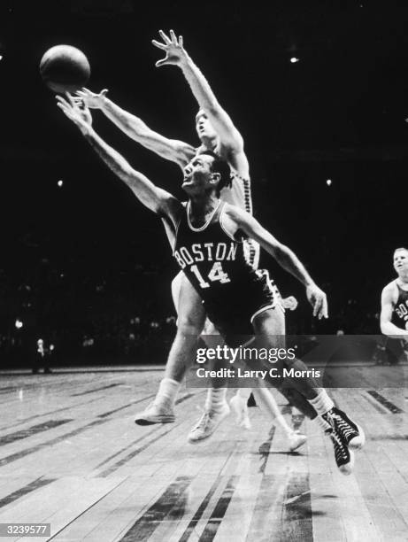 Basketball player Bob Cousy of the Celtics drives around Bob NcNeill of the Knicks to try an underhand lay-up in the Boston Celtics versus New York...