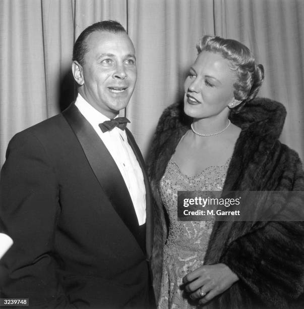 American pop singer Peggy Lee looks at publicist Frank Liberman as he speaks in front of a curtain at an event, Hollywood, California.