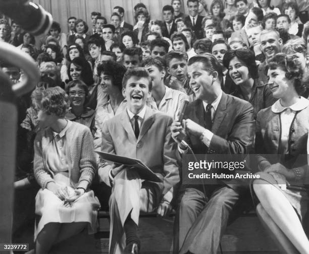 American singer and musician Bobby Rydell sits next to American television host Dick Clark in the audience of the television show, 'American...