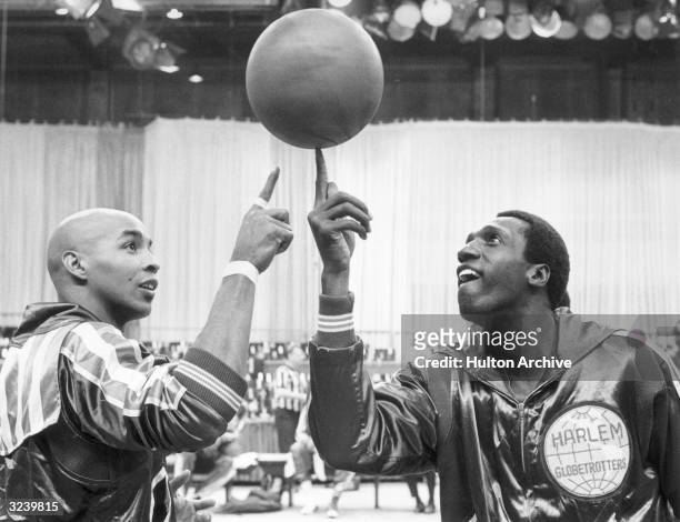 American basketball players Freddie Neal and Meadowlark Lemon of the Harlem Globetrotters pass a spinning basketball back and forth on their fingers.