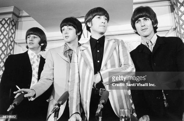 British pop group the Beatles standing in front of four microphones at a press conference where they discussed their concert at Shea Stadium, New...