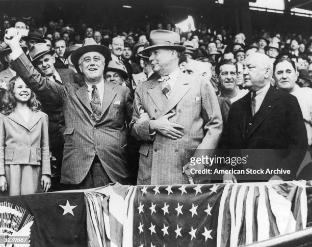 President Franklin D Roosevelt prepares to throw the first ball of baseball season while gripping the arm of his Presidential Secretary, General...