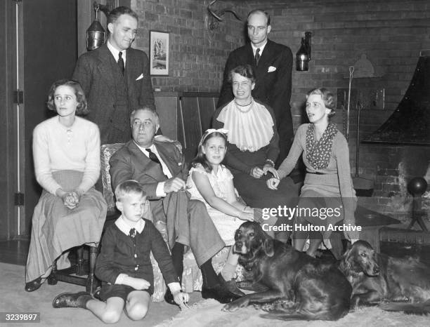 Portrait of US President Franklin D. Roosevelt seated with his family and two Irish setters in front of a fireplace, Seattle, Washington, late 1930s....