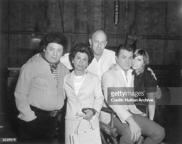 American comedian Marty Allen and American singer Nancy Sinatra pose with Sinatra's mother, Nancy Sr., and others, probably on the set of director...